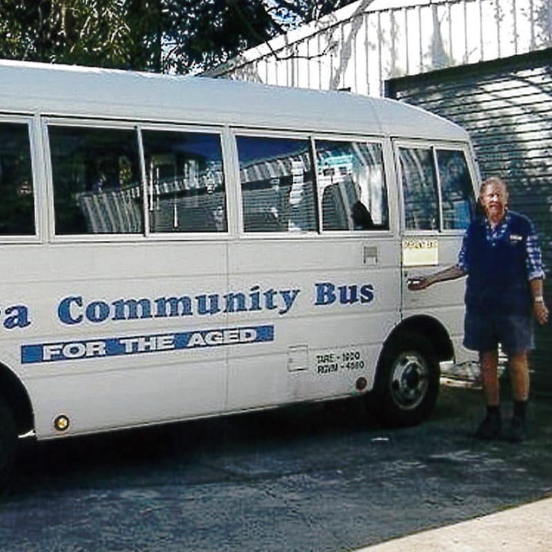 man in 1987 stands next to community transport bus